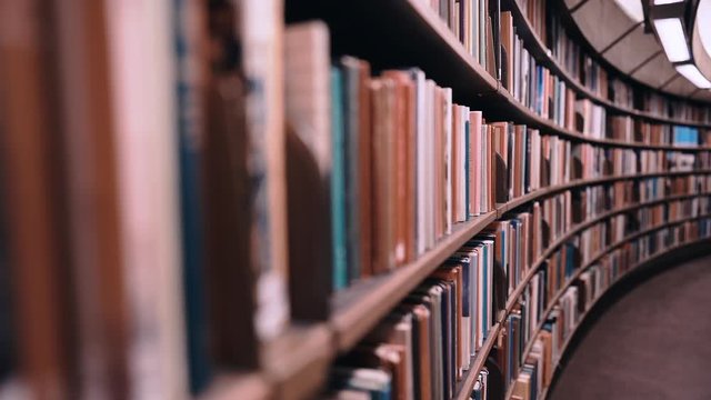 Stedicam shot. Camera moves forward along shelves filled with paper books. The huge round library in Stockholm, Sweden