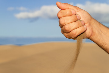 Man hand leaking sand on the a beach