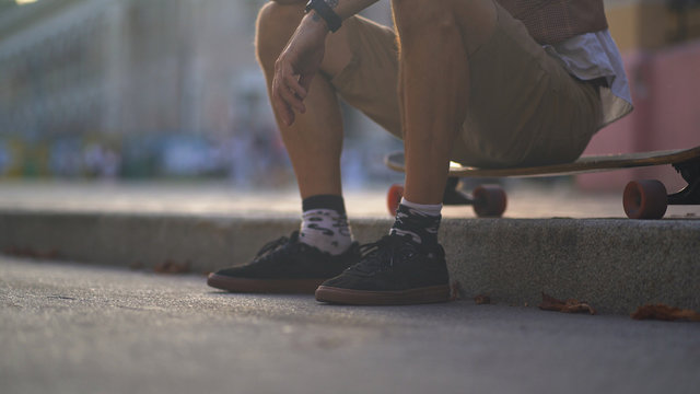 A European rests on a skateboard in the middle of a paved street