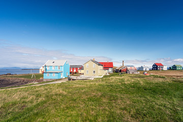 Fototapeta na wymiar Colorful buildings and the charming city of Flatey Island in Iceland just outside Stykkisholmur and the Westfjords. Blue sky and sunny weather. Explore and traveling concept