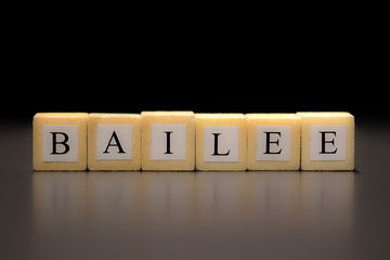 The word BAILEE written on wooden cubes isolated on a black background...