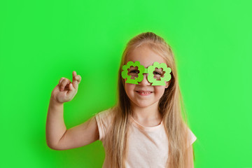 Cute Little blonde caucasian girl in mask of leprechaun shamrock clover glasses for irish St....