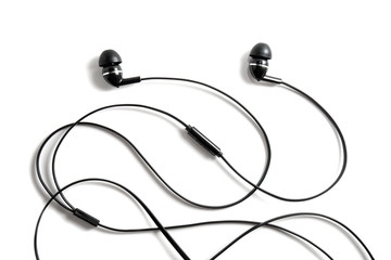 Vacuum black wired earplugs for listening to music and sound on portable devices on a white...