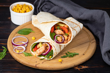 Burritos wraps with chicken and vegetables on dark background. Mexican food