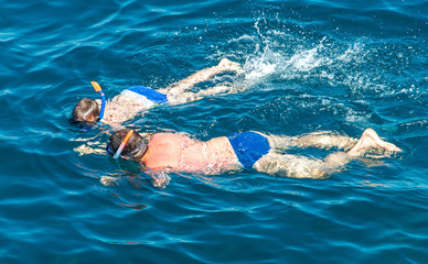 People swim in the blue water of the sea