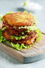 Crispy potato pancakes with green salad and yogurt sauce. Stack of potato fritters