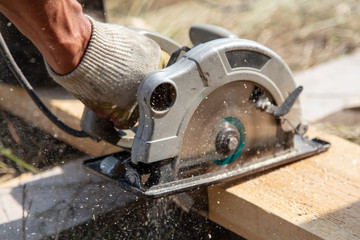 A worker cuts a wooden beam at a construction site