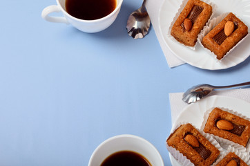 Bisquit cakes and coffee or tea cups on blue background