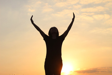 Fototapeta premium woman silhouette arms up to the sunset feeling happy and freedom.