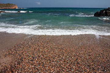 The frothy waves of the sea break on the rocks and on the beach.