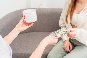 Woman paying for cosmetologist services, hand giving money, pays dollar bills.