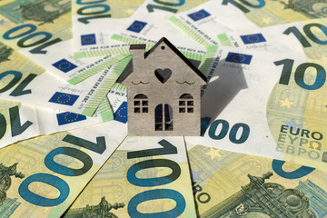 Home and money. A toy house stands on several euro banknotes. Mortgage, real estate sale, concept. Dreaming new home. Investment property. Space for text.