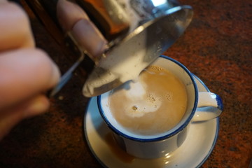 Milk foam is poured into a cup to make cappuccino