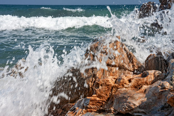 The frothy waves of the sea break on the rocks and on the beach.