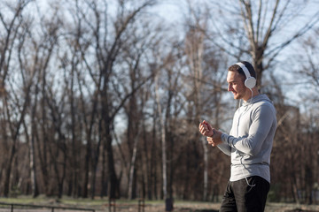 Athletic man listening music in forest with copy space