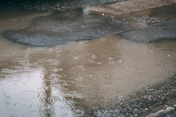 Water puddle on the street with circular shapes from rain drops
