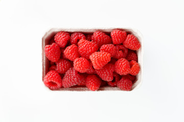 Freshly picked organic raspberries in recycled paper cup. High resolution, white background
