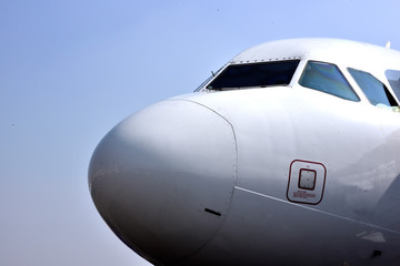 Naklejka na ściany i meble Close-up of airplane nose against blue sky background.