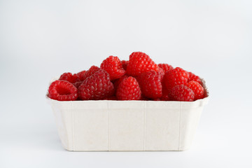 Freshly picked organic raspberries in recycled paper cup. High resolution, white background