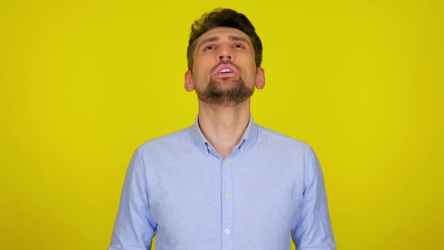 Man takes off protective mask and takes deep breath on yellow background with copy space. Epidemic precautions. Acute Respiratory Virus Infection. Illness cold flu. 4K footage.