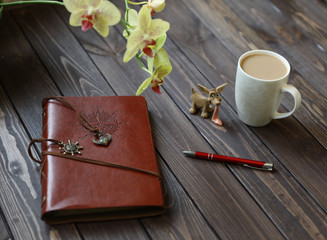notebook and cup of coffee on wooden table