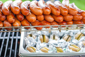 Bunch of many delicious sausages or bratwursts on a large bbq at festive event, grilling on open grill,