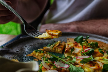 Slice of pizza on the edge of the fork, which hangs over the pizza