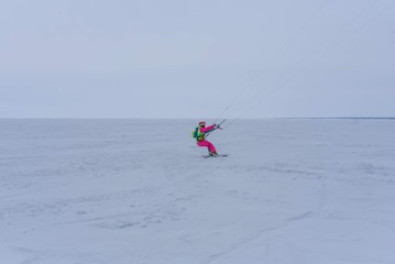 Naklejka premium Kite surfer ride on snowboard. Snowkiting in the snow on frozen lake.