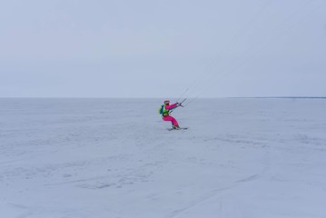 Kite surfer ride on snowboard. Snowkiting in the snow on frozen lake.