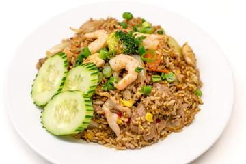Thai fried rice with shrimps ,cucumber and scallion on top , served on white plate.