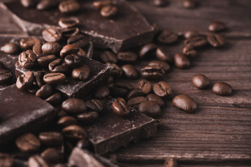 Dark chocolate with coffee beans on a dark wooden background. Sweet dessert.