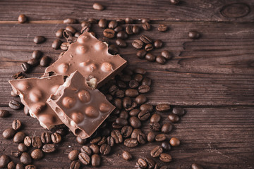 Dark chocolate with nuts and coffee beans on a dark wooden background. Sweet dessert.