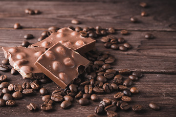 Dark chocolate with nuts and coffee beans on a dark wooden background. Sweet dessert.