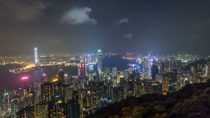 Fototapeta na wymiar Hong Kong city skyline timelapse at night with Victoria Harbor and skyscrapers illuminated by lights over water viewed from mountain top.