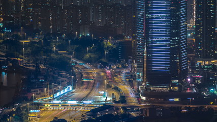 Plakat Hong Kong city skyline timelapse at night with Victoria Harbor and skyscrapers illuminated by lights over water viewed from mountain top.