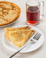 Crepes or pancake with tea on light background. Vertical orientation.