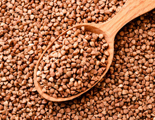 Buckwheat in a wooden spoon. Buckwheat background top view