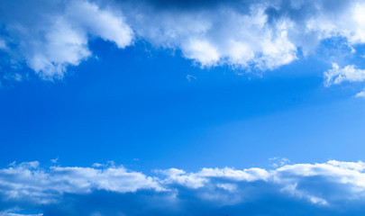 Fototapeta premium Blue sky with clouds on the top and the bottom of the composition and free space in the centre.