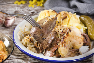 Fried liver with onion and apple, served with boiled potatoes and pickled cucumber.