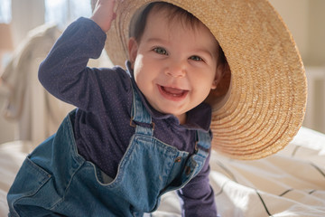 Little infant girl in straw hat smiling and laughing. Family lifestyle