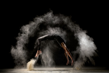 Male gymnast jumping in dust cloud profile view