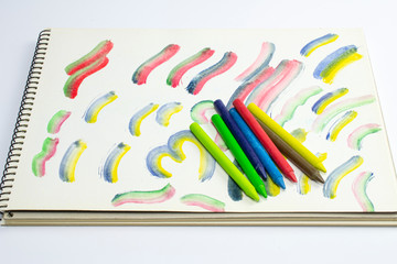 Opened album with baby pattern and wax pencil near the albom page isolated on white