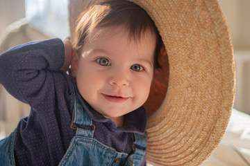 Little infant girl in straw hat smiling and laughing. Family lifestyle