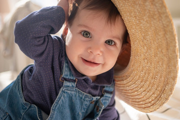 Little infant girl in straw hat smiling and laughing. Family lifestyle