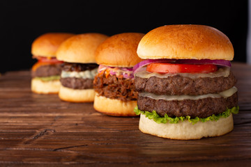 Perspective photo of four hamburgers on rustic setting