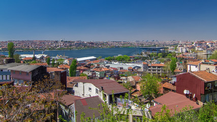 Fototapeta na wymiar Panoramic top view with red roofs of houses and mosques behind Golden Horn timelapse in Istanbul, Turkey.