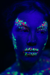 Woman with fluorescent make-up looking away