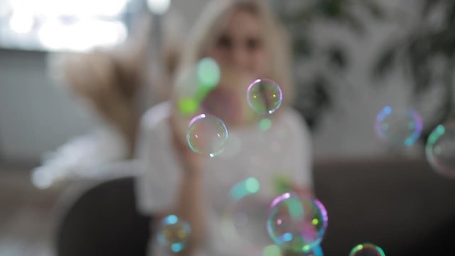 Woman blowing soap bubbles at home