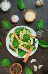 Healthy salad of chicken breast, fresh vegetables, spinach leaves, avocado on a dark background. Salad of greens with meat. The concept of diet food. Copy space.