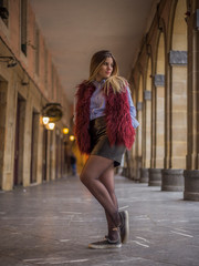 Street style, a young caucasian blonde in an urban photo session, under some houses